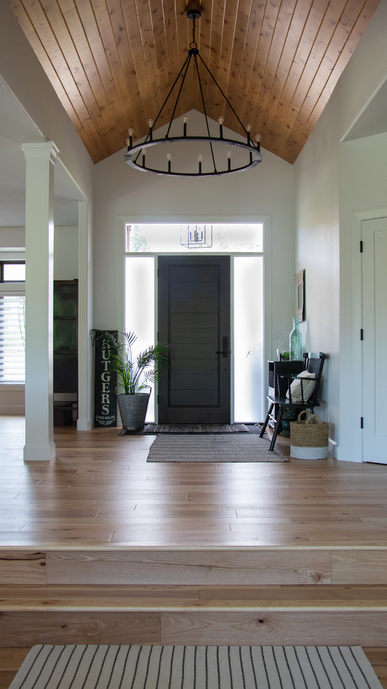 Inspiration for a transitional foyer in Portland with white walls, light hardwood floors, a single front door, a dark wood front door and brown floor.