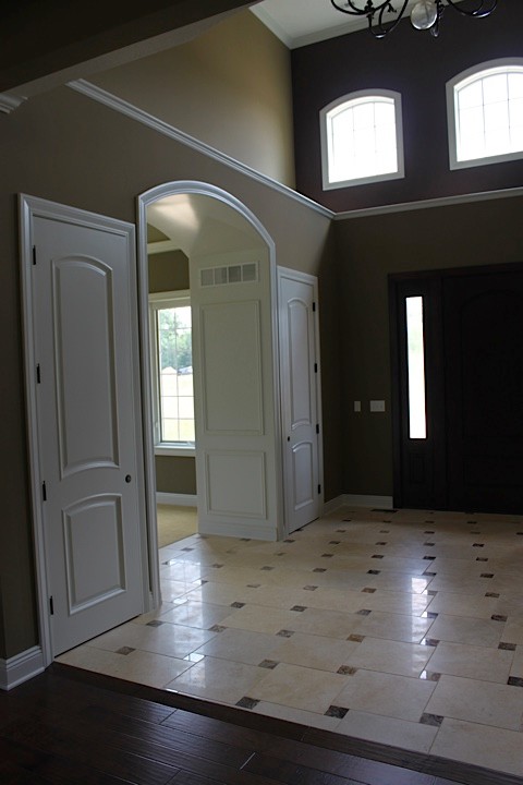 Idées déco pour un hall d'entrée classique avec un mur vert, un sol en calcaire, une porte simple et une porte en bois foncé.