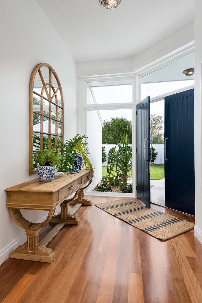 Large beach style foyer in Gold Coast - Tweed with white walls, medium hardwood flooring, a double front door and a blue front door.