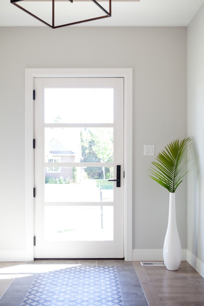 На фото: узкая прихожая среднего размера в стиле кантри с белыми стенами, паркетным полом среднего тона, одностворчатой входной дверью, коричневым полом и стеклянной входной дверью с