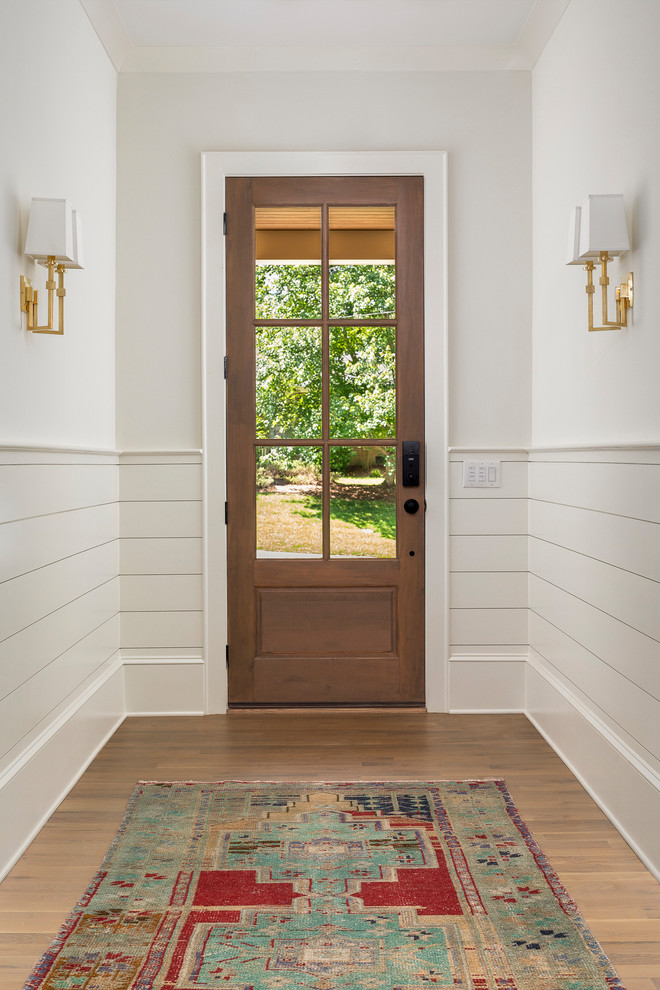 Ejemplo de distribuidor clásico renovado de tamaño medio con paredes beige, suelo de madera en tonos medios, puerta simple y puerta de madera en tonos medios