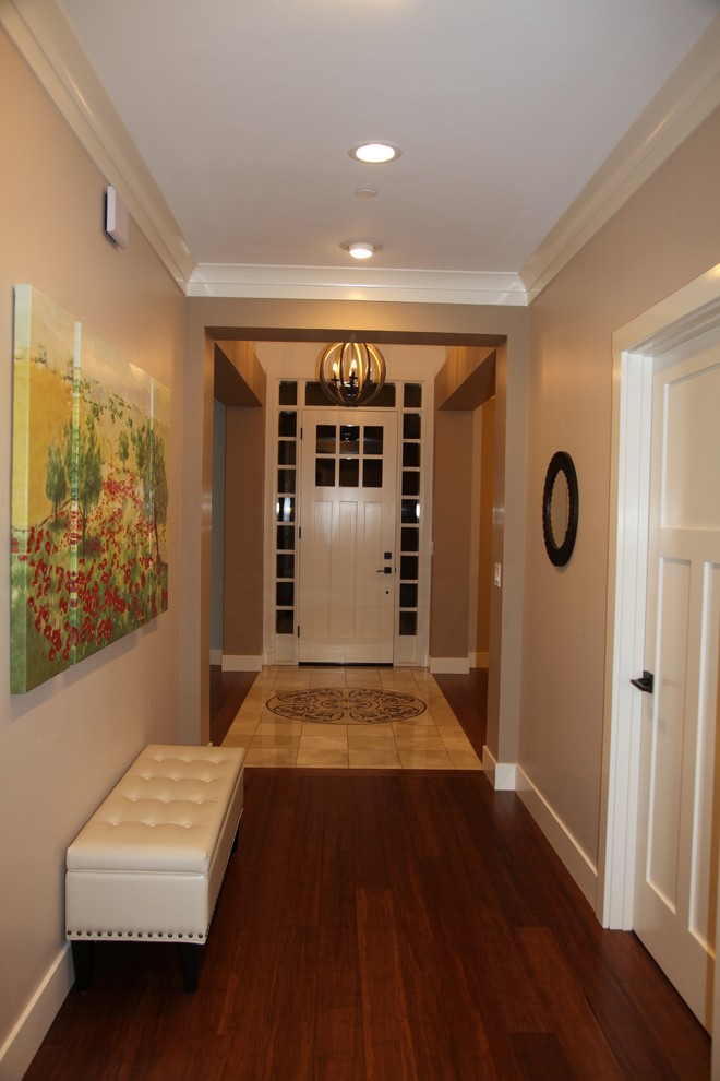 Cette photo montre une entrée craftsman de taille moyenne avec un couloir, un mur beige, parquet foncé, une porte simple et une porte blanche.