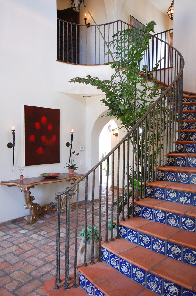 Large tuscan brick floor entryway photo in Los Angeles with white walls and a dark wood front door