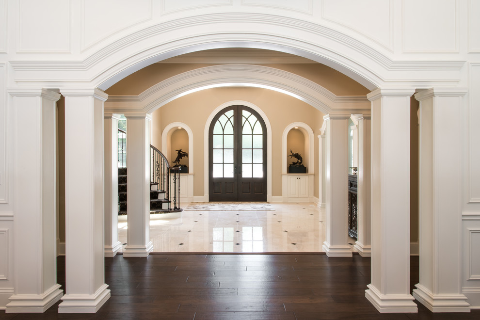 Geräumiges Klassisches Foyer mit beiger Wandfarbe, Marmorboden, Doppeltür, dunkler Holzhaustür und weißem Boden in Sonstige