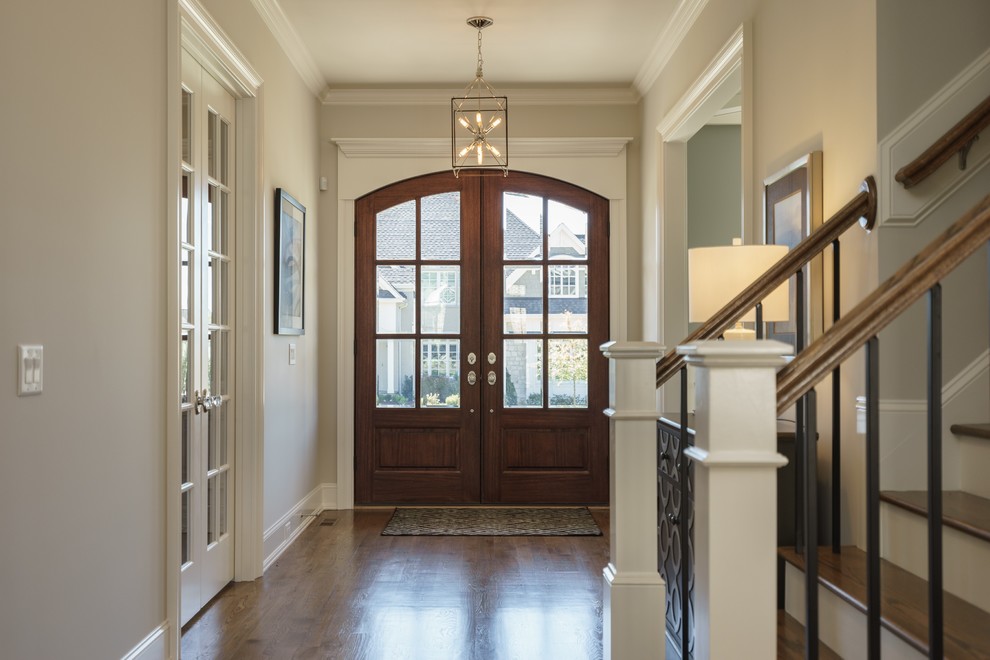 Immagine di un ingresso o corridoio chic con pareti beige, pavimento in legno massello medio, una porta a due ante, una porta in legno bruno e pavimento marrone