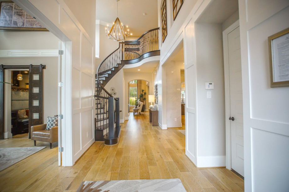 Example of a large trendy light wood floor foyer design in Houston with white walls