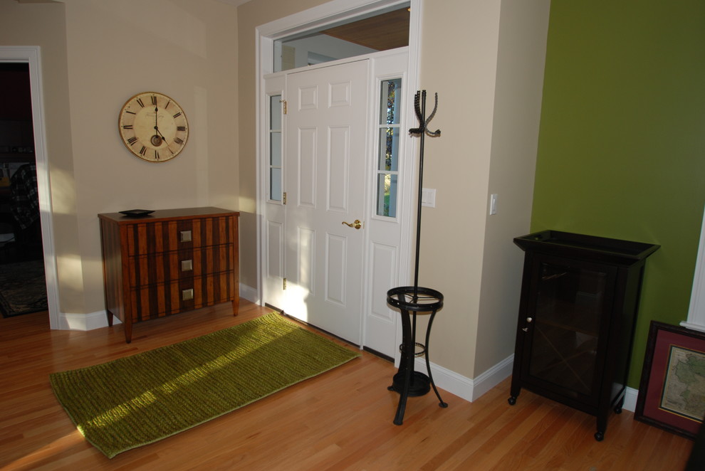 Cette photo montre une grande porte d'entrée chic avec un mur vert et un sol en bois brun.
