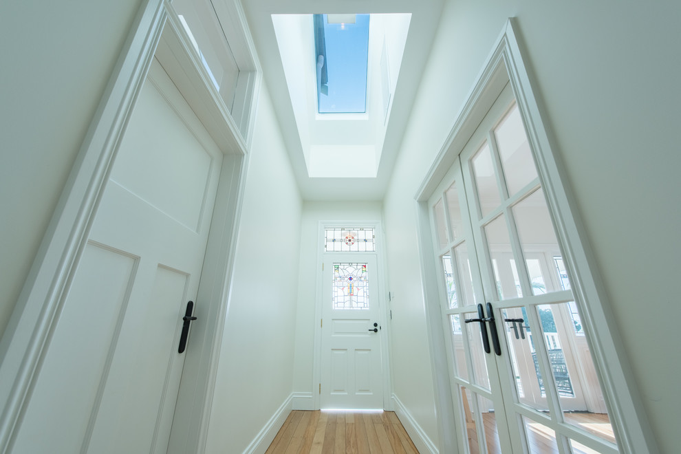 Immagine di un ingresso o corridoio classico con pareti bianche, pavimento in legno massello medio, una porta singola, una porta in vetro e pavimento marrone