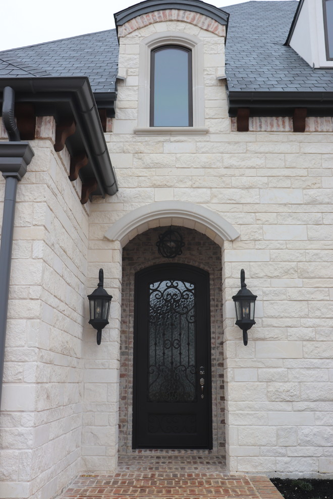Example of a large classic brick floor and multicolored floor entryway design in Dallas with beige walls and a black front door
