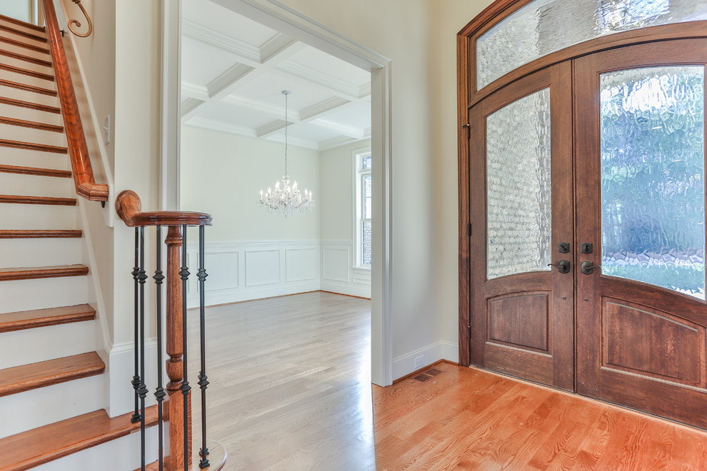Imagen de puerta principal tradicional de tamaño medio con paredes beige, suelo de madera en tonos medios, puerta doble y puerta de madera oscura