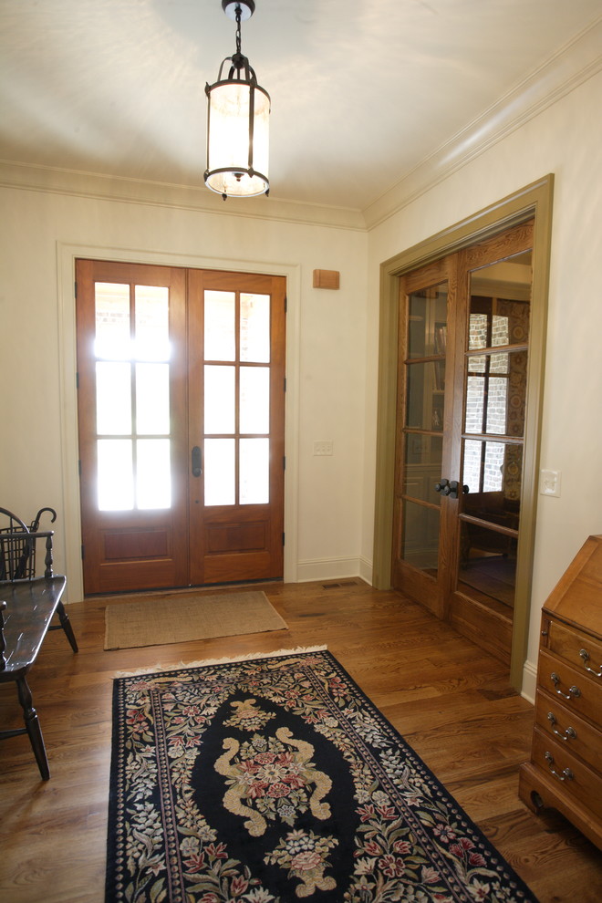 Imagen de puerta principal tradicional con paredes blancas, suelo de madera en tonos medios, puerta doble y puerta de madera en tonos medios