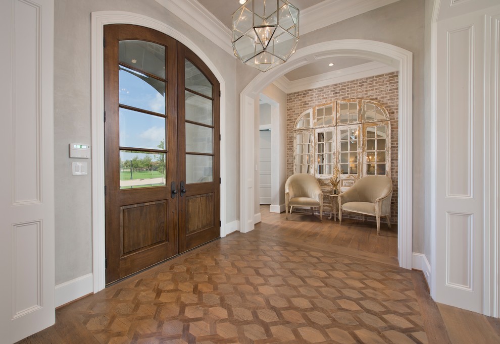 Imagen de puerta principal de tamaño medio con paredes grises, suelo de madera en tonos medios, puerta doble, puerta de madera oscura y suelo marrón