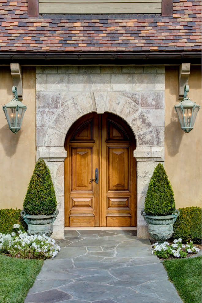 Bild på en ingång och ytterdörr, med en dubbeldörr, mellanmörk trädörr, beige väggar och grått golv