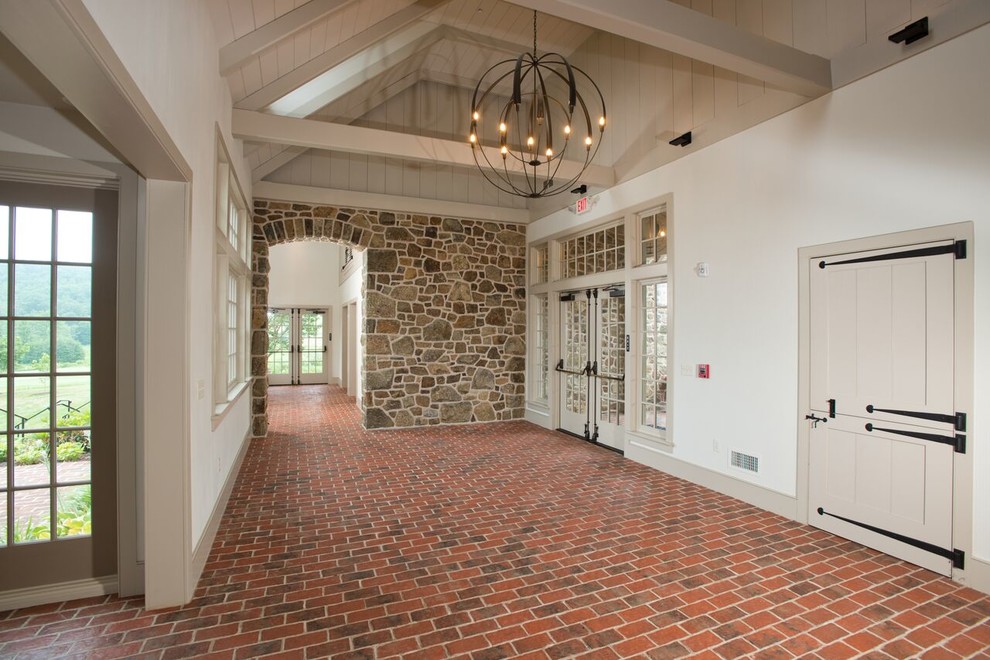 Foto di un corridoio tradizionale di medie dimensioni con pareti bianche, pavimento in mattoni, una porta a due ante, una porta in vetro e pavimento rosso
