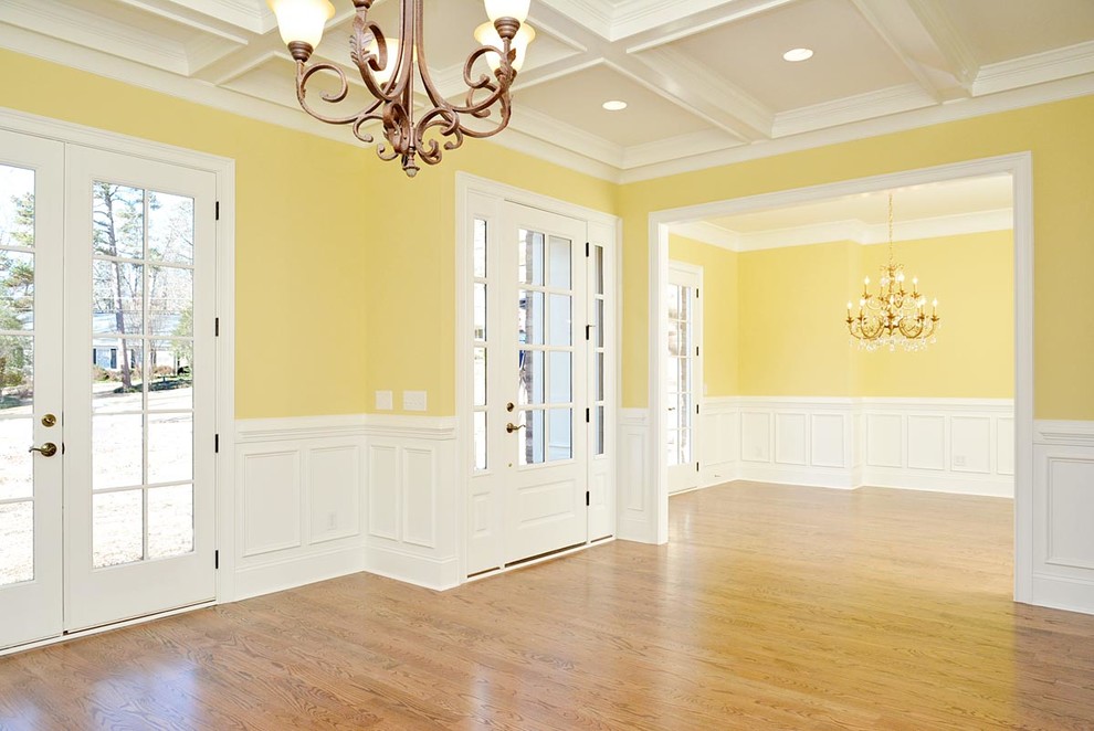 Idées déco pour un grand hall d'entrée montagne avec un mur jaune, un sol en bois brun, une porte simple et une porte blanche.