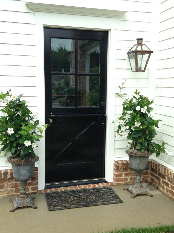 This is an example of a small traditional front door in New Orleans with white walls, a single front door and a black front door.