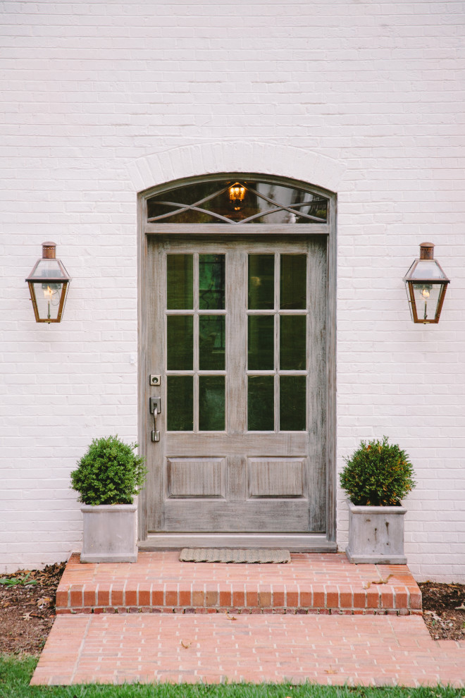 На фото: входная дверь в стиле неоклассика (современная классика) с белыми стенами, одностворчатой входной дверью и серой входной дверью