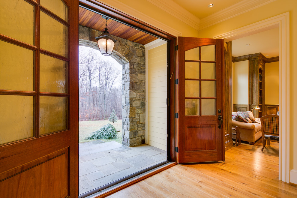 Ispirazione per una grande porta d'ingresso tradizionale con pareti gialle, parquet chiaro, una porta a due ante e una porta in legno bruno