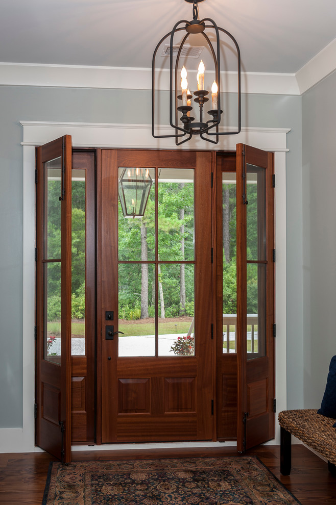 На фото: входная дверь среднего размера в стиле неоклассика (современная классика) с паркетным полом среднего тона, синими стенами, одностворчатой входной дверью и входной дверью из темного дерева