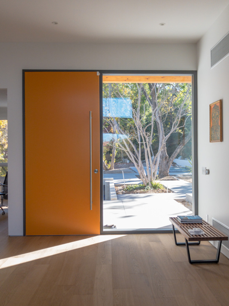 Foto di un grande ingresso moderno con pareti bianche, pavimento in legno massello medio, una porta singola, una porta arancione e pavimento marrone