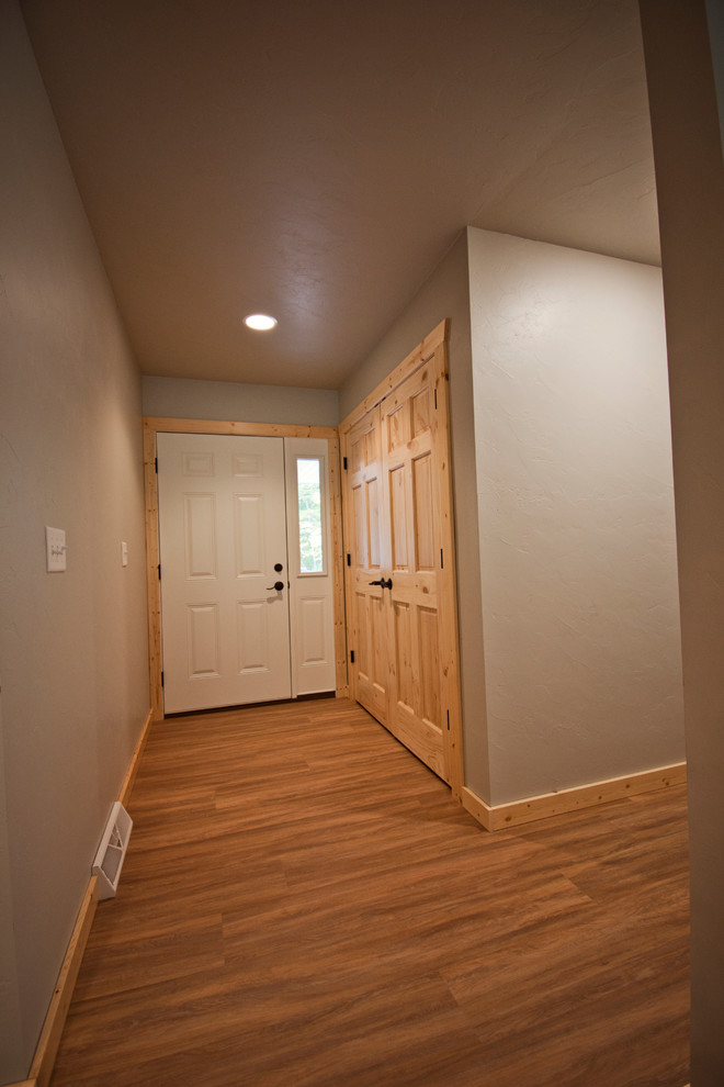 Diseño de puerta principal rústica de tamaño medio con paredes beige, suelo de madera en tonos medios, puerta simple, puerta blanca y suelo marrón