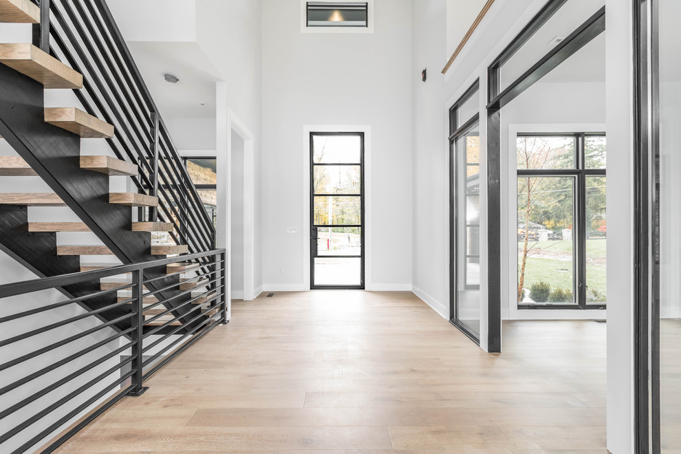 Immagine di un grande ingresso minimalista con pareti bianche, pavimento in legno massello medio, una porta singola, una porta in vetro e pavimento marrone