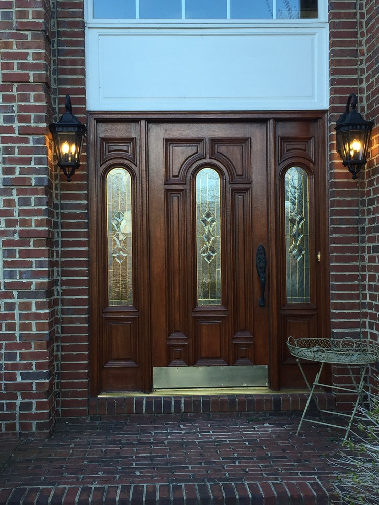 На фото: большая входная дверь в классическом стиле с красными стенами, кирпичным полом, двустворчатой входной дверью, входной дверью из темного дерева и красным полом
