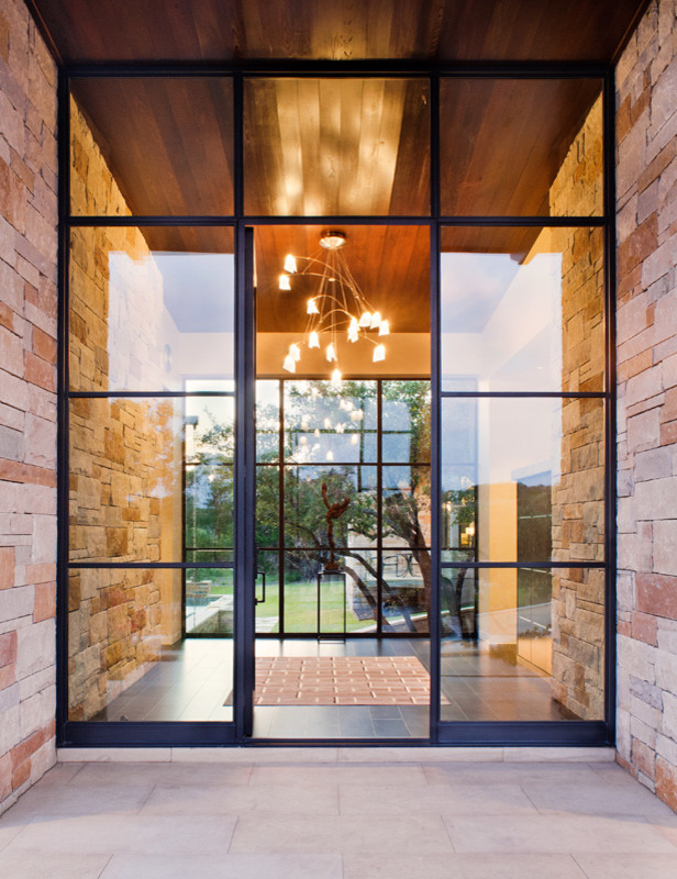 オースティンにある広いコンテンポラリースタイルのおしゃれな玄関ドア (ベージュの壁、コンクリートの床、ガラスドア、グレーの床) の写真
