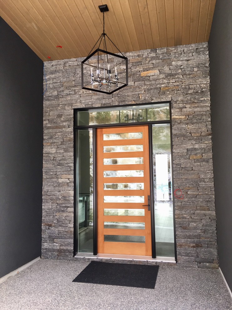 Foto de puerta principal moderna con paredes negras, suelo de cemento, puerta simple, puerta de madera en tonos medios y suelo gris