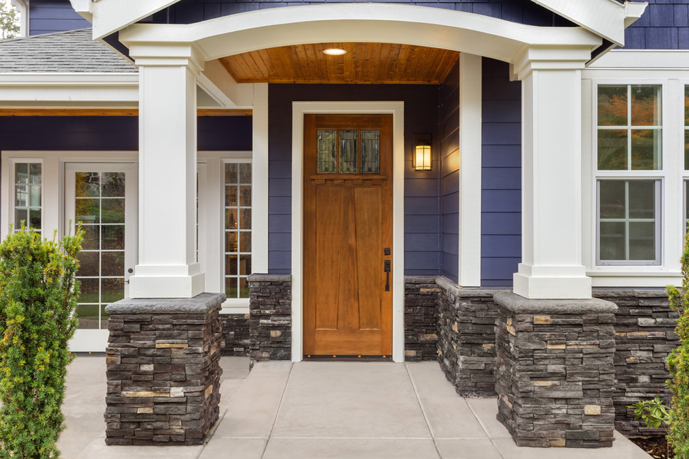 Exempel på en mellanstor amerikansk ingång och ytterdörr, med lila väggar, betonggolv, en enkeldörr och mellanmörk trädörr