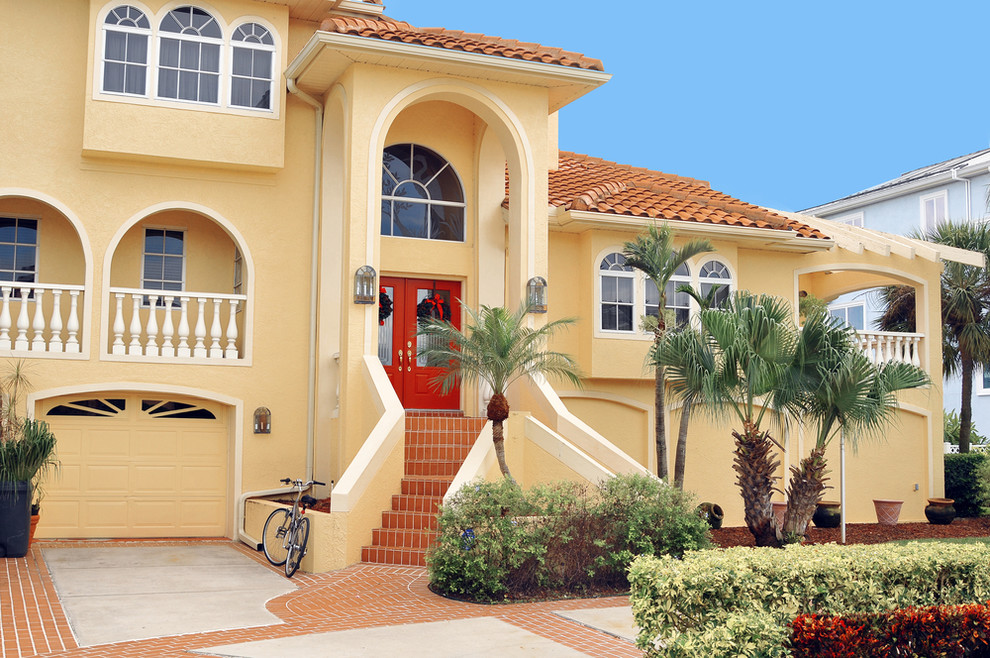 Inspiration for a large mediterranean front door in Tampa with yellow walls, a double front door and a red front door.