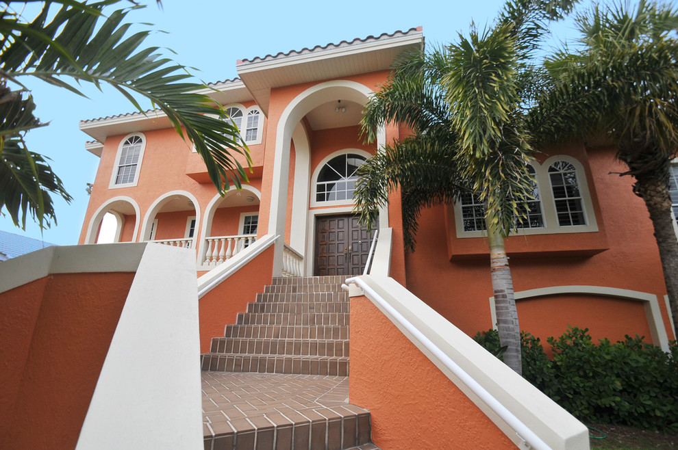 Photo of a large mediterranean front door in Tampa with orange walls, a double front door and a dark wood front door.