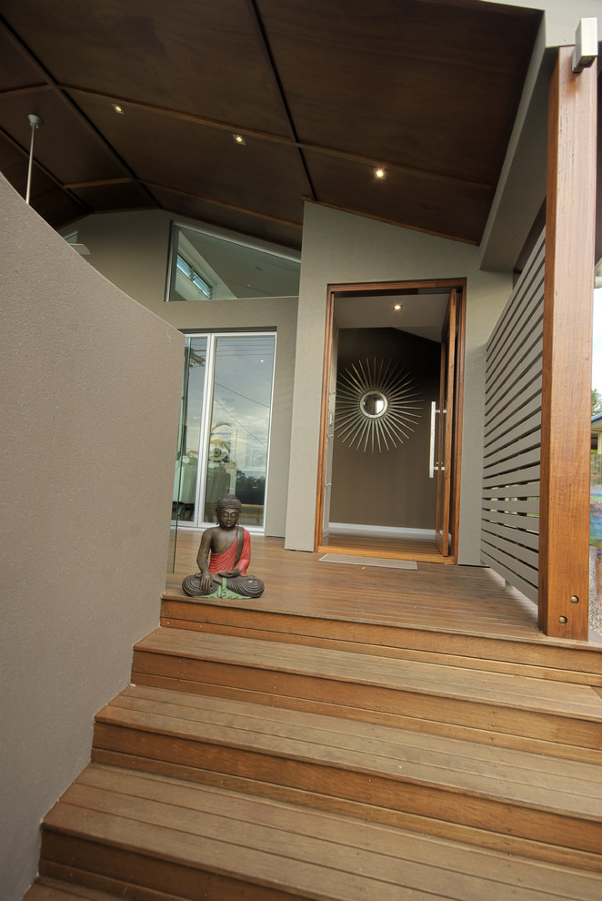 Cette image montre une entrée design avec une porte en verre et un sol en bois brun.