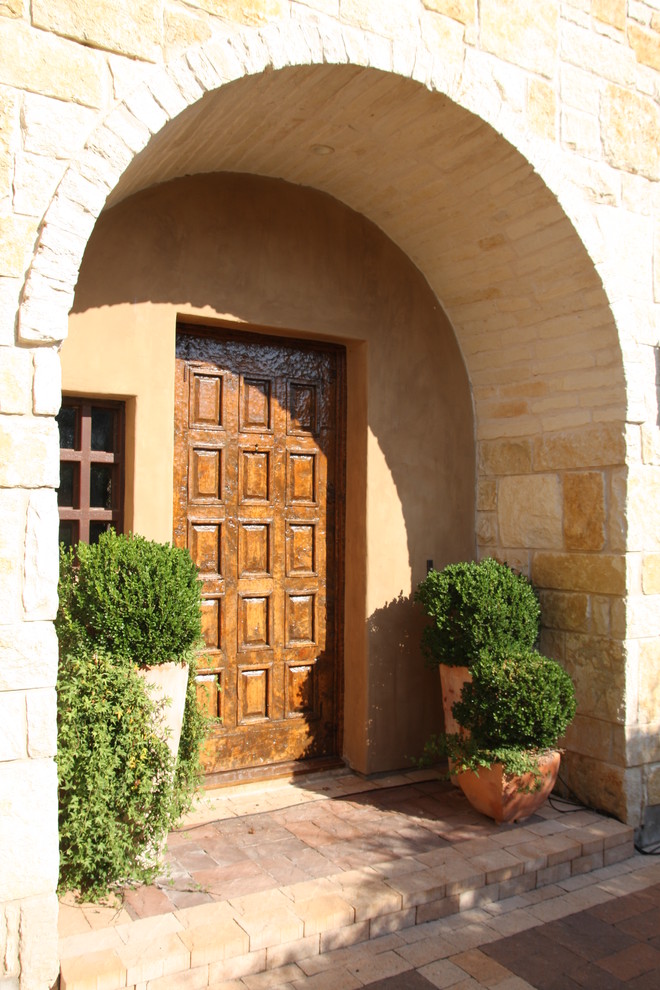 Cette image montre une entrée méditerranéenne avec une porte simple et une porte en bois foncé.