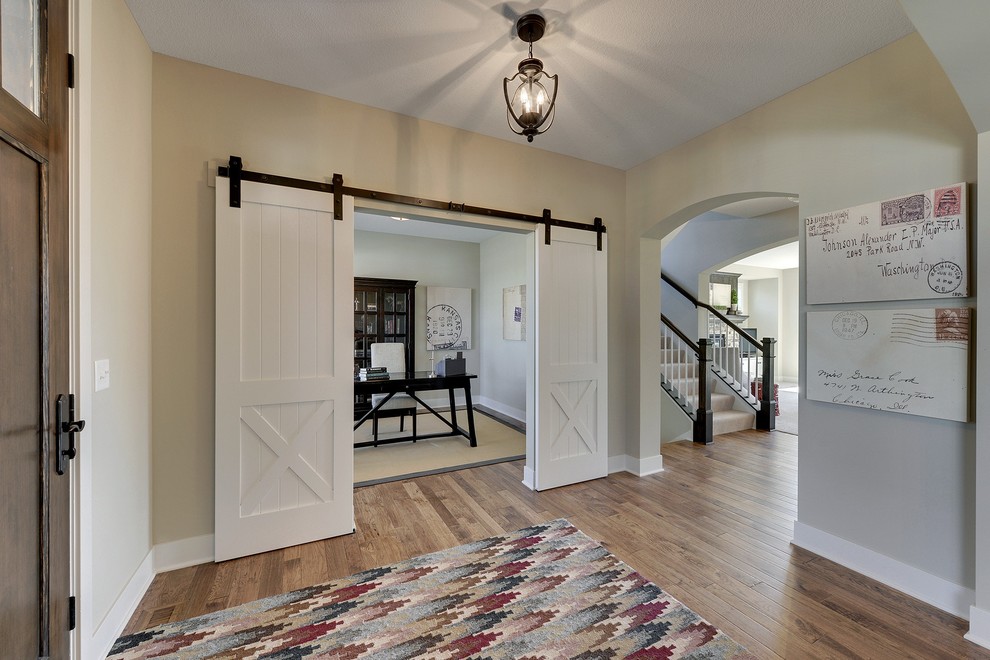 Example of a large transitional medium tone wood floor entryway design in Minneapolis with beige walls and a dark wood front door