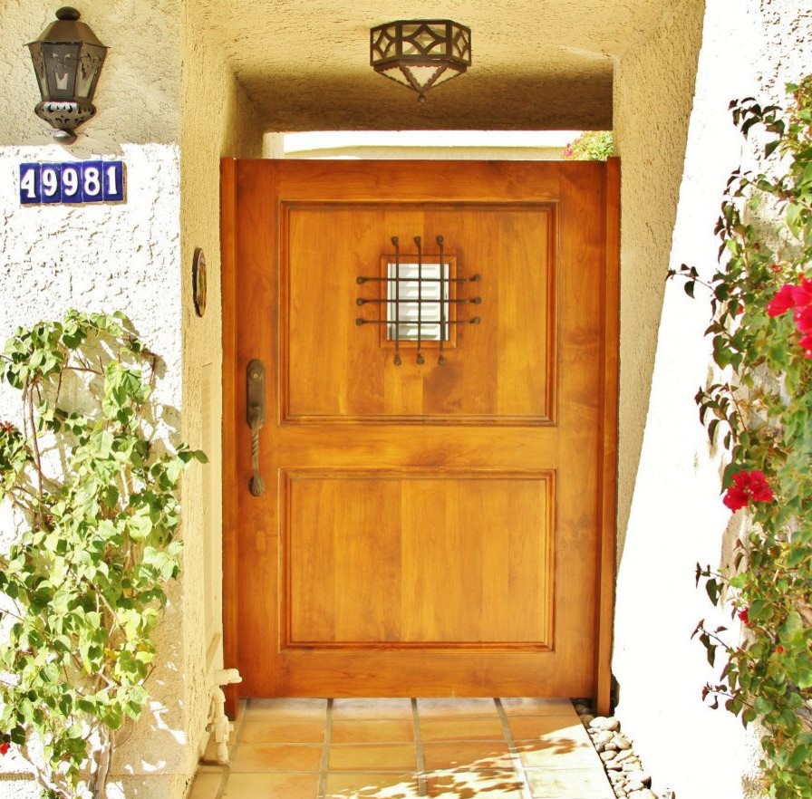 Modelo de puerta principal mediterránea con suelo de baldosas de terracota, puerta simple y puerta de madera en tonos medios