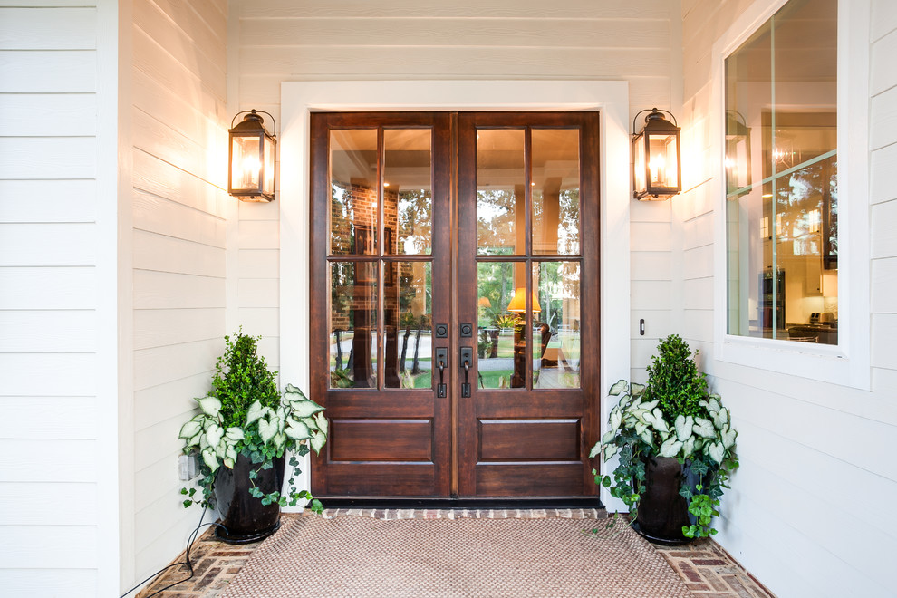 This is an example of a large farmhouse front door in Dallas with white walls, a double front door, a dark wood front door and multi-coloured floors.