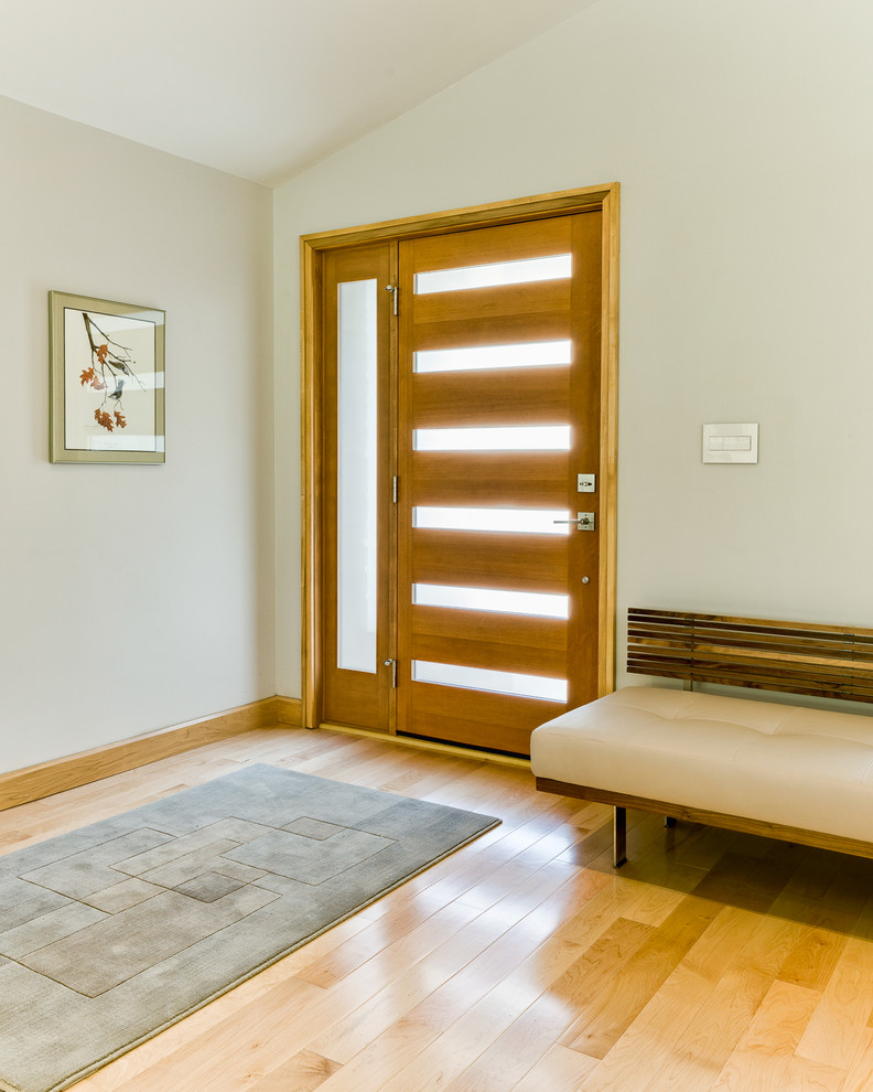 Réalisation d'une grande porte d'entrée minimaliste avec parquet clair, une porte simple, une porte en bois foncé et un mur beige.