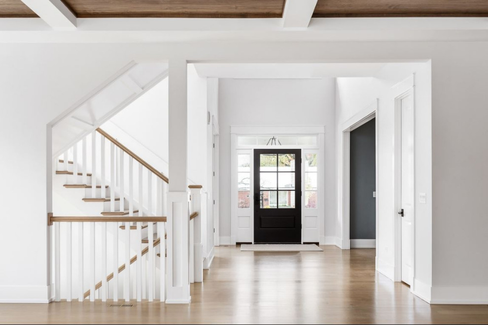 Design ideas for a large rural foyer in Chicago with white walls, light hardwood flooring, a black front door, brown floors and a vaulted ceiling.
