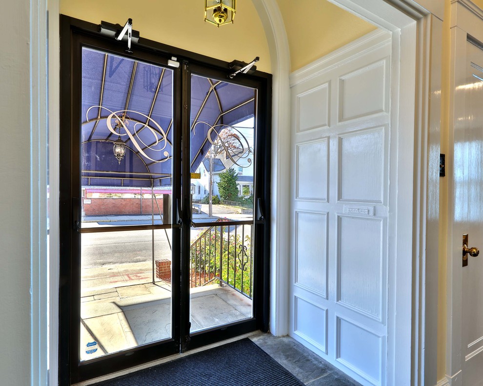 Esempio di una porta d'ingresso tradizionale con pareti gialle, pavimento in ardesia, una porta a due ante e una porta in vetro