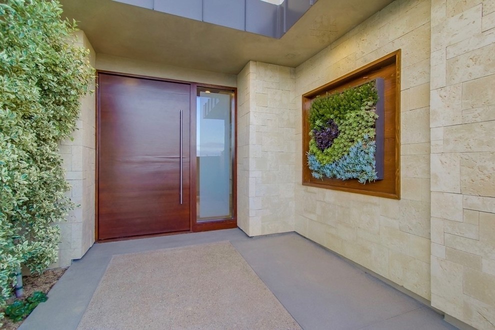 Cette photo montre une grande porte d'entrée tendance avec sol en béton ciré, une porte pivot, une porte en bois brun et un sol gris.