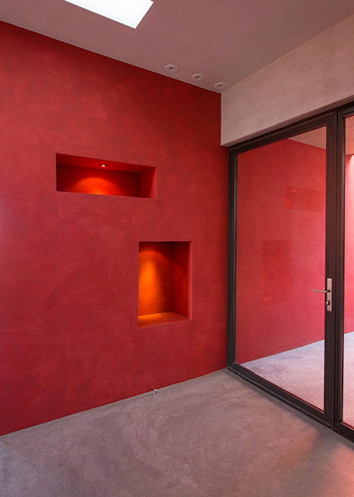 Идея дизайна: входная дверь среднего размера в современном стиле с красными стенами, бетонным полом, поворотной входной дверью и стеклянной входной дверью