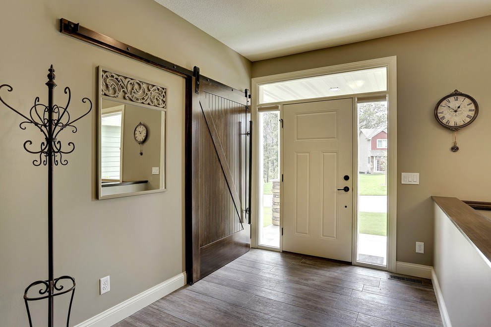 Modelo de puerta principal de estilo americano grande con paredes beige, suelo de madera oscura, puerta simple y puerta blanca