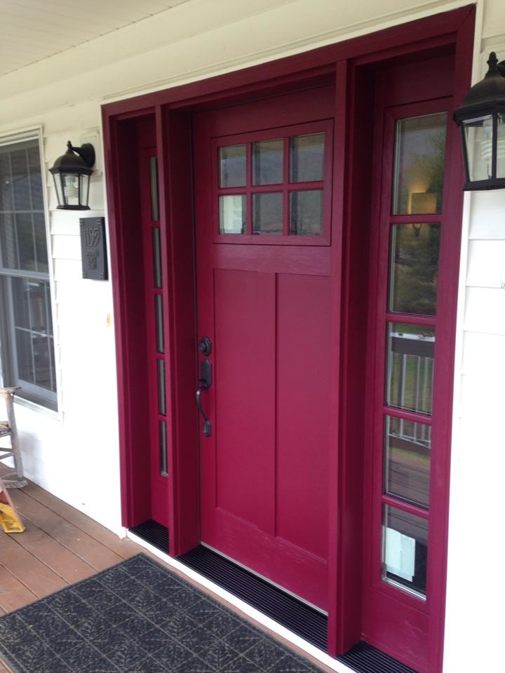 Modelo de entrada clásica grande con paredes blancas, suelo de madera en tonos medios, puerta simple y puerta roja