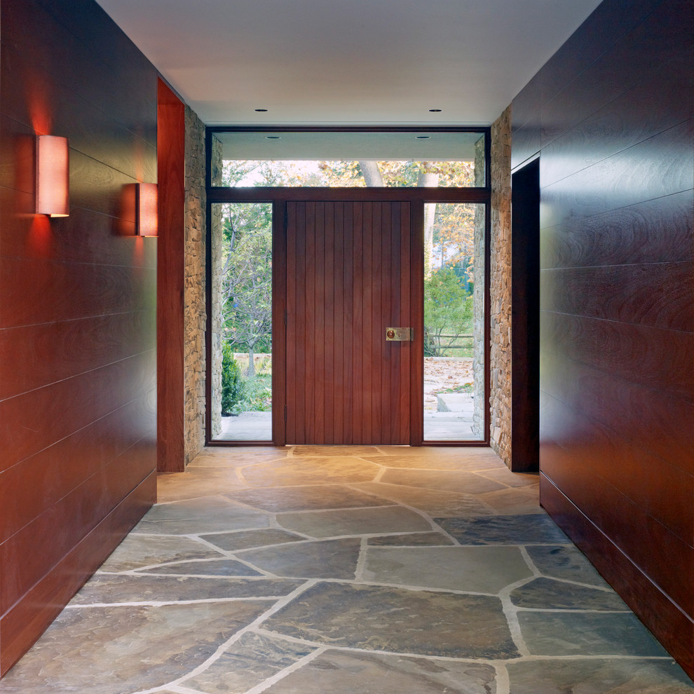 Пример оригинального дизайна: узкая прихожая среднего размера в современном стиле с коричневыми стенами, полом из травертина, поворотной входной дверью, входной дверью из дерева среднего тона и бежевым полом