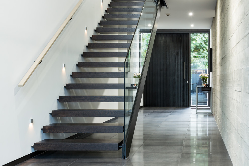 Aménagement d'un hall d'entrée contemporain de taille moyenne avec un mur gris, une porte simple, une porte noire et un sol gris.