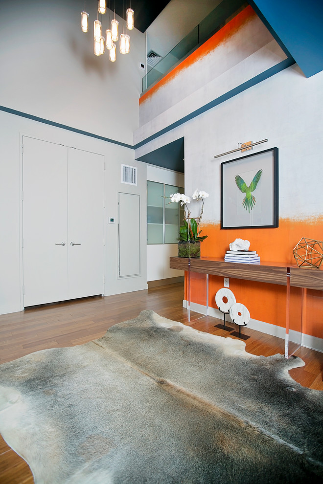 На фото: фойе среднего размера в современном стиле с оранжевыми стенами, паркетным полом среднего тона, двустворчатой входной дверью и серой входной дверью с