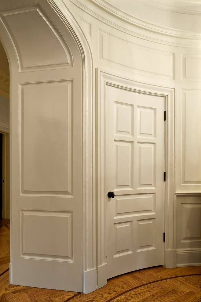 Modelo de puerta principal tradicional de tamaño medio con paredes blancas, suelo de madera clara, puerta simple y puerta de madera oscura