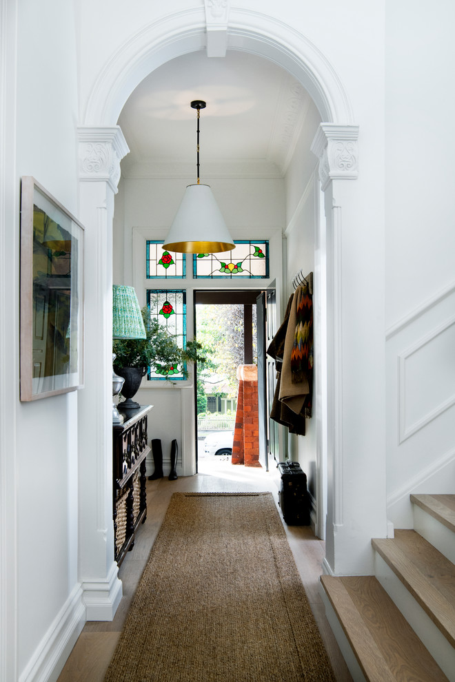 На фото: узкая прихожая в классическом стиле с белыми стенами, паркетным полом среднего тона, одностворчатой входной дверью и коричневым полом с