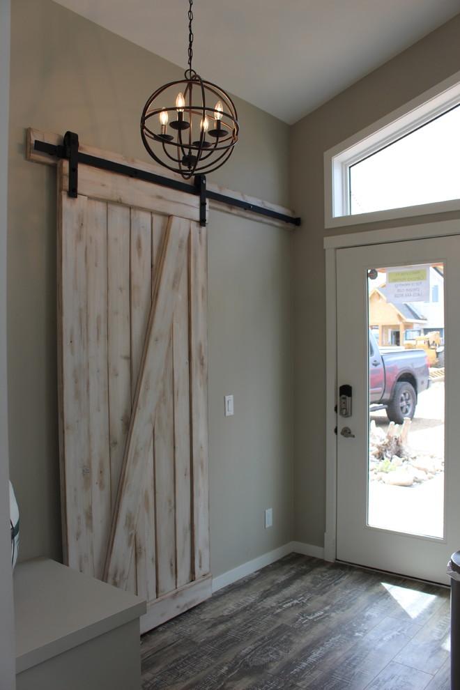 Modelo de puerta principal marinera pequeña con paredes beige, puerta simple, suelo de madera en tonos medios y puerta blanca
